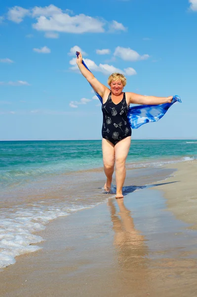 Aktive reife Frau läuft den Strand — Stockfoto