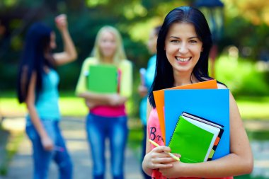 mutlu kız öğrenci ile renkli kitaplar açık havada