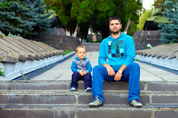 benzer baba ve oğul parkta merdivenlerde oturan