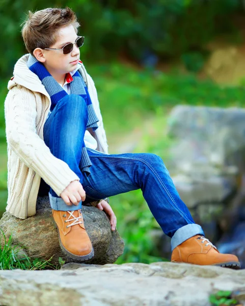 Adolescent élégant garçon assis sur le rocher à l'extérieur — Photo