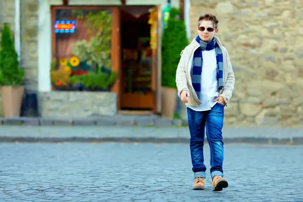 Stylish teenage boy crossing the street of old town — Stock Photo, Image