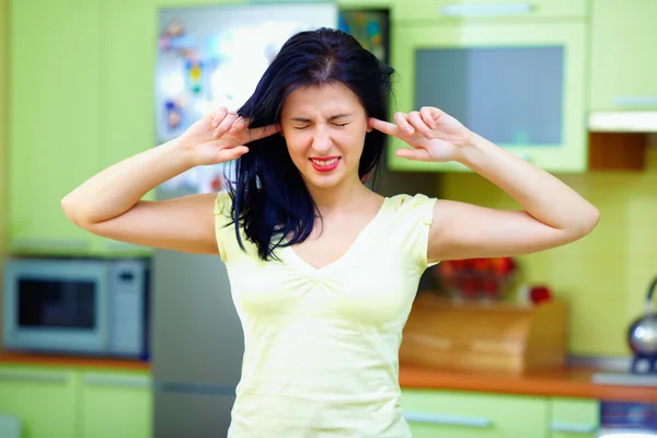 Mujer enojada cierra los oídos con los dedos, interior del hogar —  Fotos de Stock
