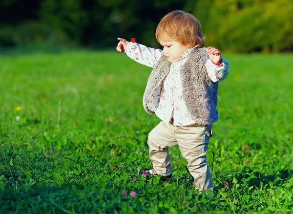 Cute baby girl making first steps, colorful outdoors — Stock Photo, Image