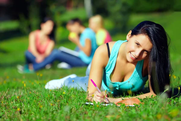 Beautiful student girl relaxing in green park on background — Stock Photo, Image