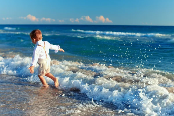 Gelukkig babyjongen plezier op het strand. focus op surf — Stockfoto