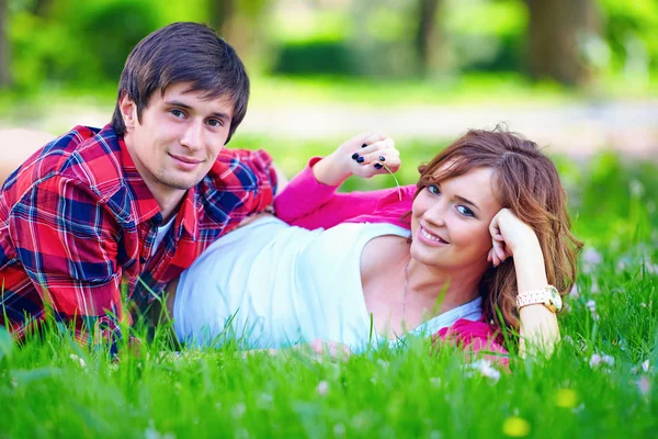 Beau jeune couple couché dans l'herbe de printemps — Photo