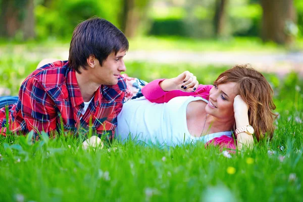Hermosa pareja joven acostada en la hierba de primavera — Foto de Stock