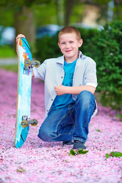 Adolescente con patín en jardín de primavera — Foto de Stock