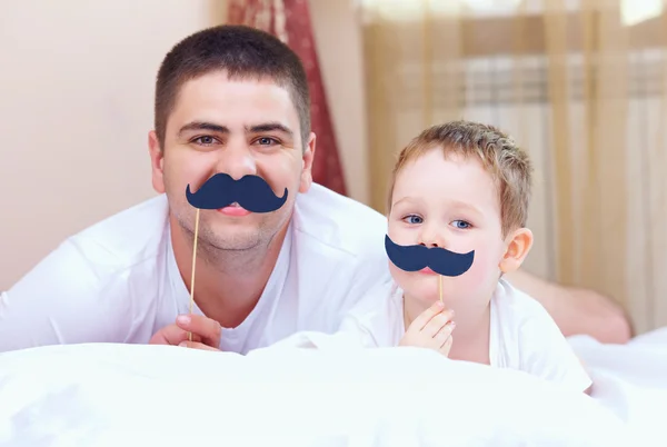 Drôle père et fils avec de fausses moustaches, jouer à la maison — Photo