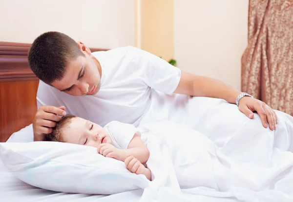 Vader kijken naar die de zoon, home binnenshuis slaapt — Stockfoto