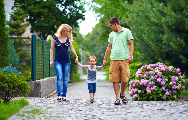 Familia feliz de tres personas caminando por la calle — Foto de Stock