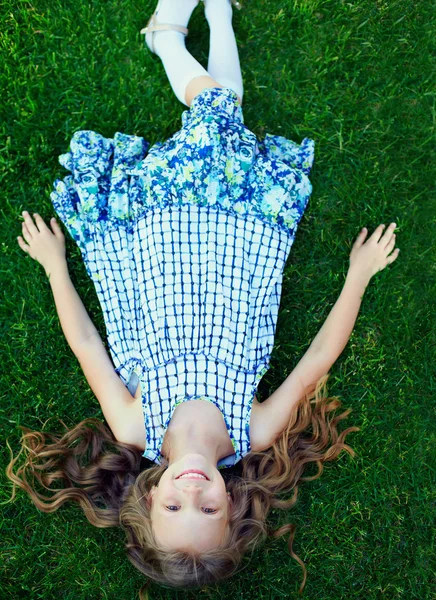 Όμορφη κοπέλα ευτυχισμένη παιδί που βρίσκεται στο πράσινο γρασίδι — Φωτογραφία Αρχείου