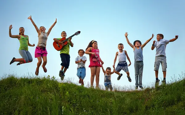 Happy kids jumping on summer field — Stock Photo, Image