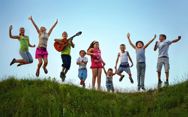 Niños felices saltando en el campo de verano Fotos de stock