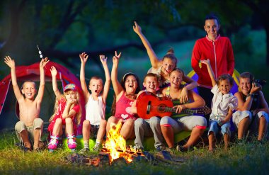happy kids singing songs around camp fire clipart