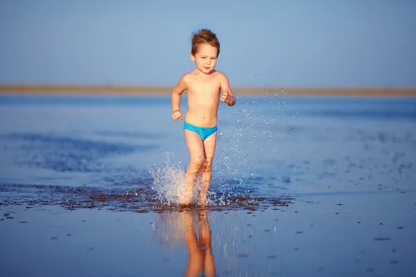 Roztomilý chlapec dítě běží na jezero — Stock fotografie