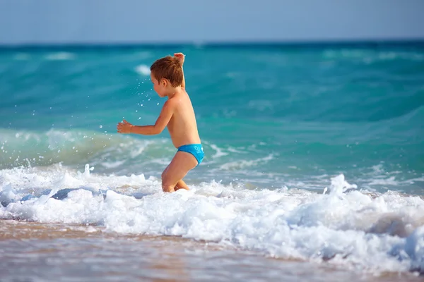 Fröhlicher Junge, der Spaß im Meerwasser hat — Stockfoto