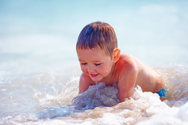 Fröhlicher Junge, der Spaß im Meerwasser hat — Stockfoto