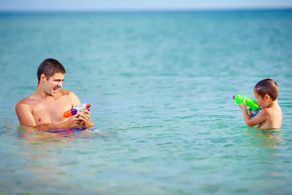 Happy father and son playing with water pistols — Stock Photo, Image
