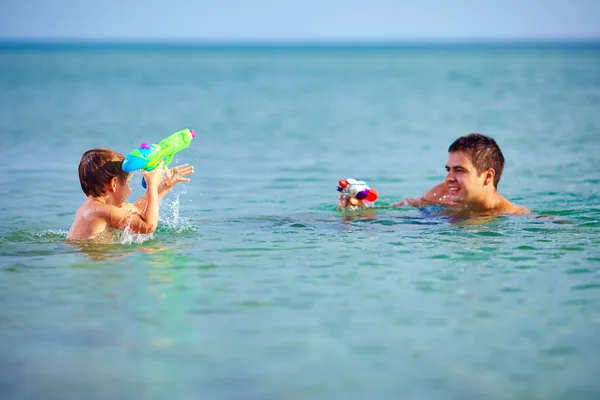 happy father and son playing with water pistols