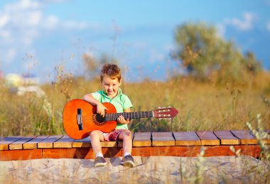 bir gitar yaz sahada oynayan sevimli çocuk portresi