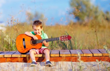 bir gitar yaz sahada oynayan sevimli çocuk portresi