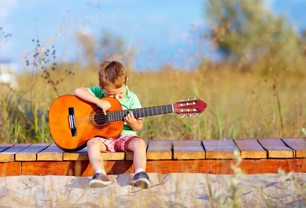 Aranyos fiú gitározni a nyári mező portréja — Stock Fotó