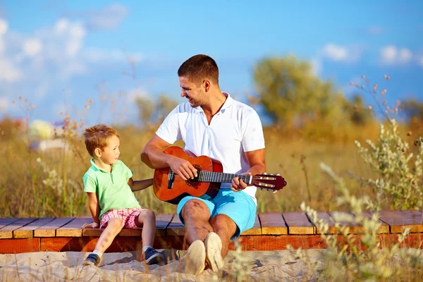 Porträt eines süßen Jungen, der eine Gitarre auf dem Sommerfeld spielt — Stockfoto