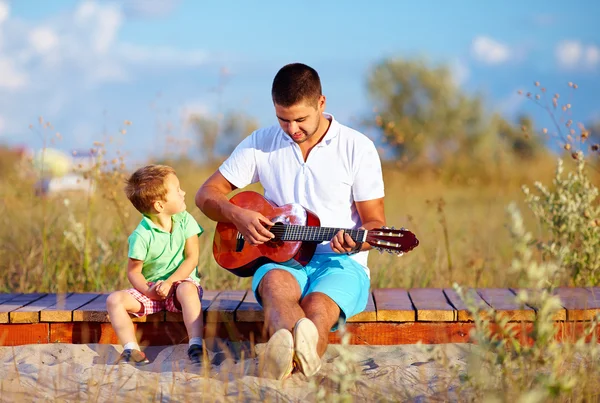 Retrato de chico lindo tocando una guitarra en el campo de verano —  Fotos de Stock