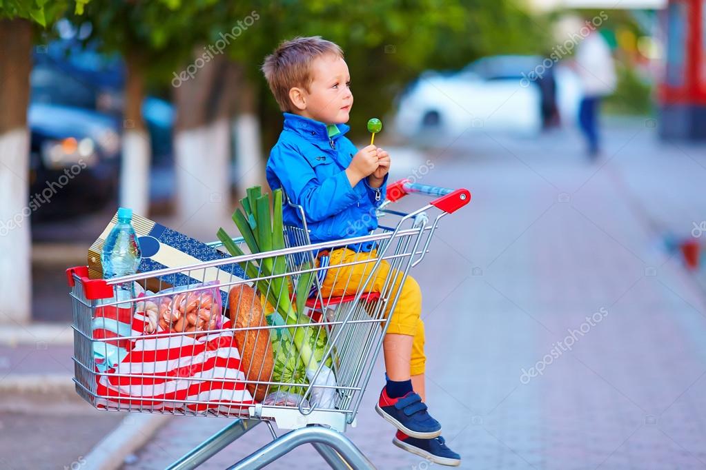 Kid in trolley full of foodstuffs after shopping — Stock Photo
