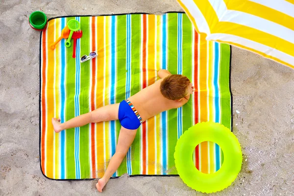 Bonito garoto tomando banho de sol na praia colorida — Fotografia de Stock