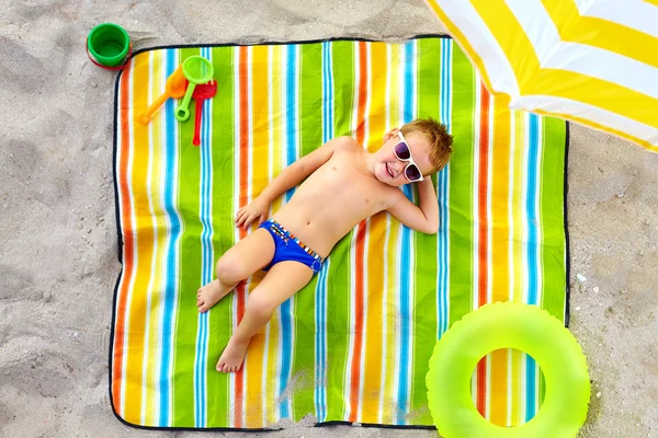 Criança feliz tomando banho de sol na praia colorida — Fotografia de Stock