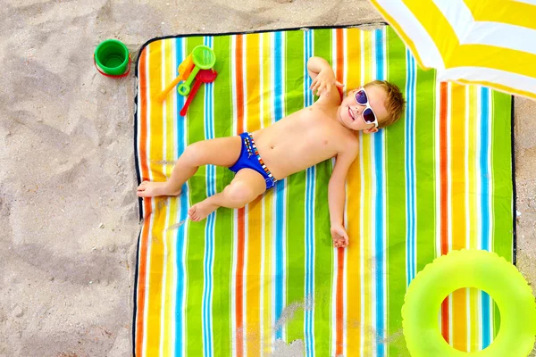 Glückliches Kind sonnt sich am bunten Strand — Stockfoto