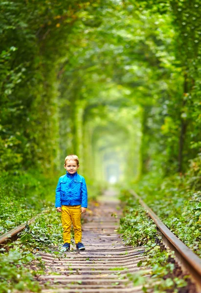 Niño sonriente caminando los rieles en tonel verde — Foto de Stock