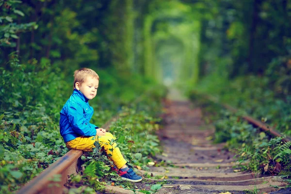 Niño triste sentado sobre rieles en tonel verde —  Fotos de Stock