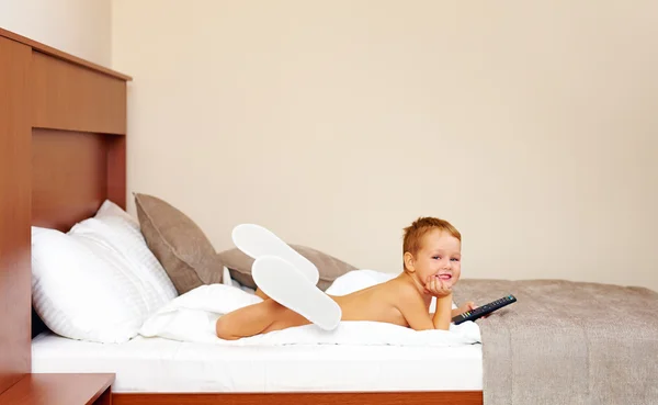 Niño feliz viendo la televisión en la habitación del hotel después de bañarse —  Fotos de Stock