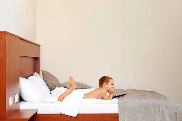 Bambino felice guardando la tv in camera d'albergo dopo il bagno — Foto Stock