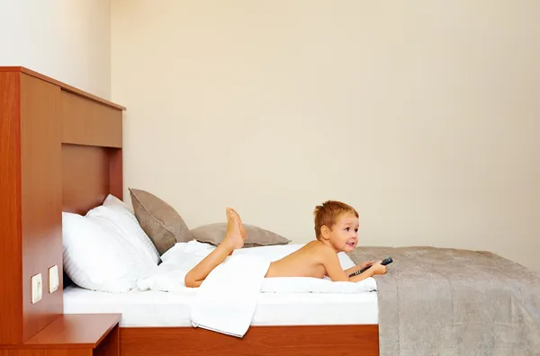 Criança feliz assistindo tv no quarto de hotel após o banho — Fotografia de Stock