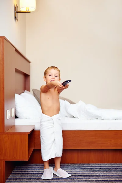 Criança feliz assistindo tv no quarto de hotel após o banho — Fotografia de Stock