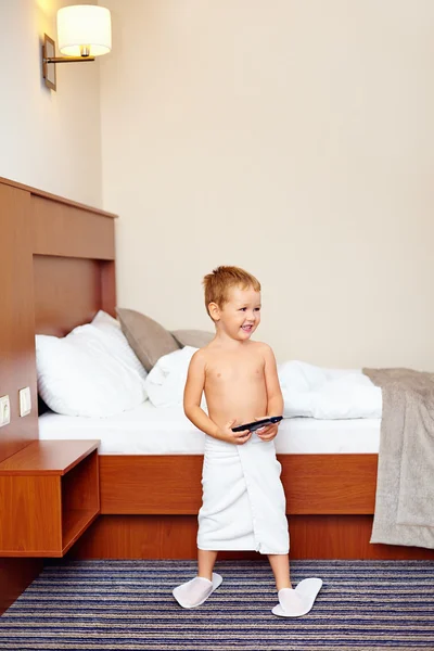 Criança feliz assistindo tv no quarto de hotel após o banho — Fotografia de Stock