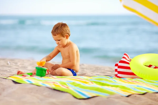 Χαριτωμένο παιδί που παίζει με τα παιχνίδια στην άμμο στην παραλία — Φωτογραφία Αρχείου