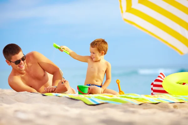 Gelukkig vader en kind plezier in zand op het strand — Stockfoto