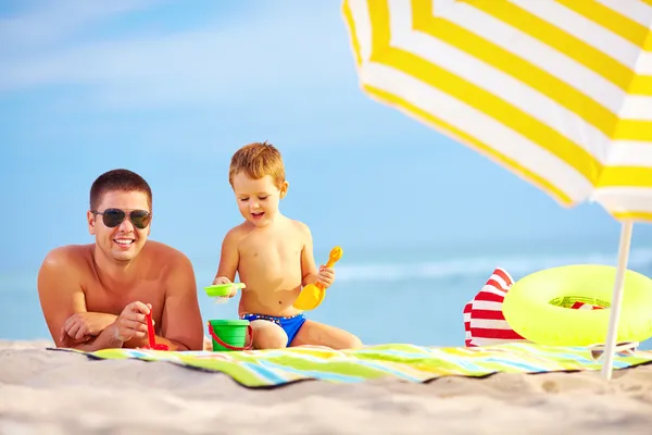 Heureux père et enfant s'amuser dans le sable sur la plage — Photo