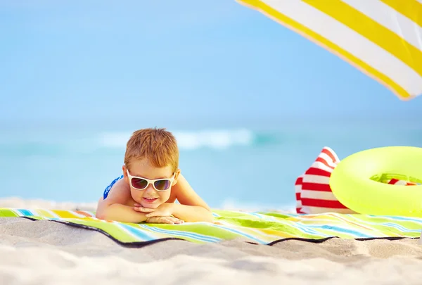 Cute kid in sunglasses resting on colorful beach — Stock Photo, Image