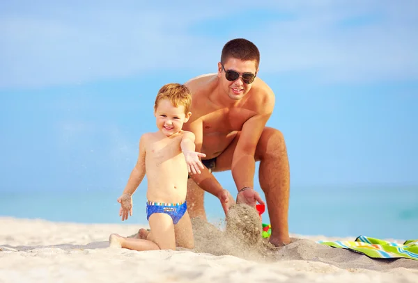 Щасливий батько і син розважаються в піску на пляжі — стокове фото