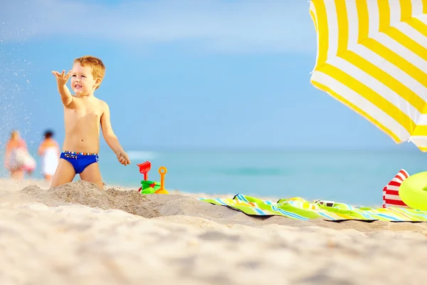 Bambino attivo che gioca nella sabbia sulla spiaggia — Foto Stock