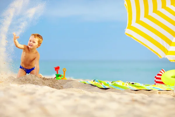 Garoto ativo brincando na areia na praia — Fotografia de Stock