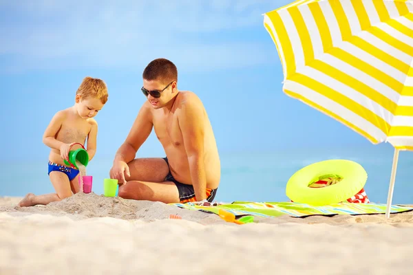 Mutlu baba ve çocuk oyuncakları kumsalda oynarken — Stok fotoğraf