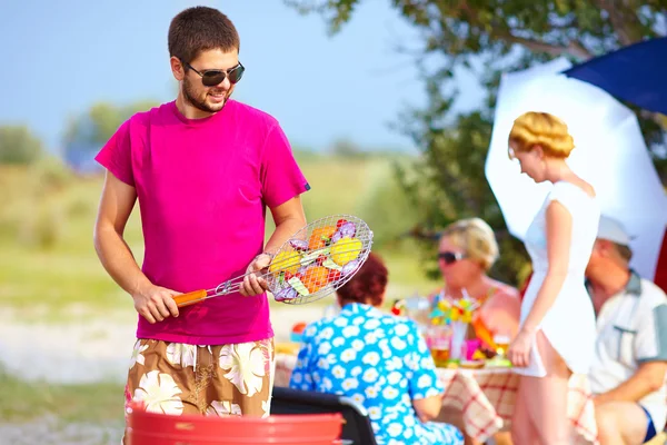 Homme heureux prépare la nourriture sur le gril, pique-nique en famille — Photo