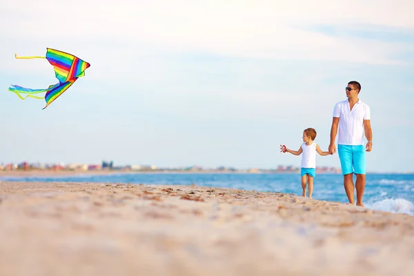Feliz padre e hijo jugando con cometa en la playa de verano — Foto de Stock